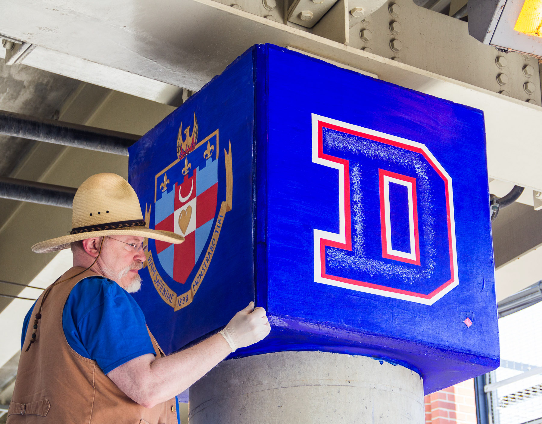 Brother Mark Elder, C.M., puts the finishes touches on the decorative top of a pillar. Last summer, Elder and a group of students added four new murals to "The Story of the Little School Under the 'L'" project. (DePaul University/Russell Dorn)